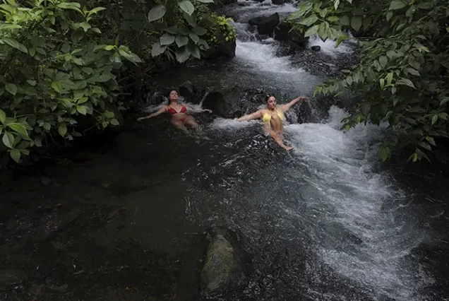 Bathing and relaxing in the warm waters of a small rainforest river, near volcanic hot springs in La Fortuna, Costa Rica